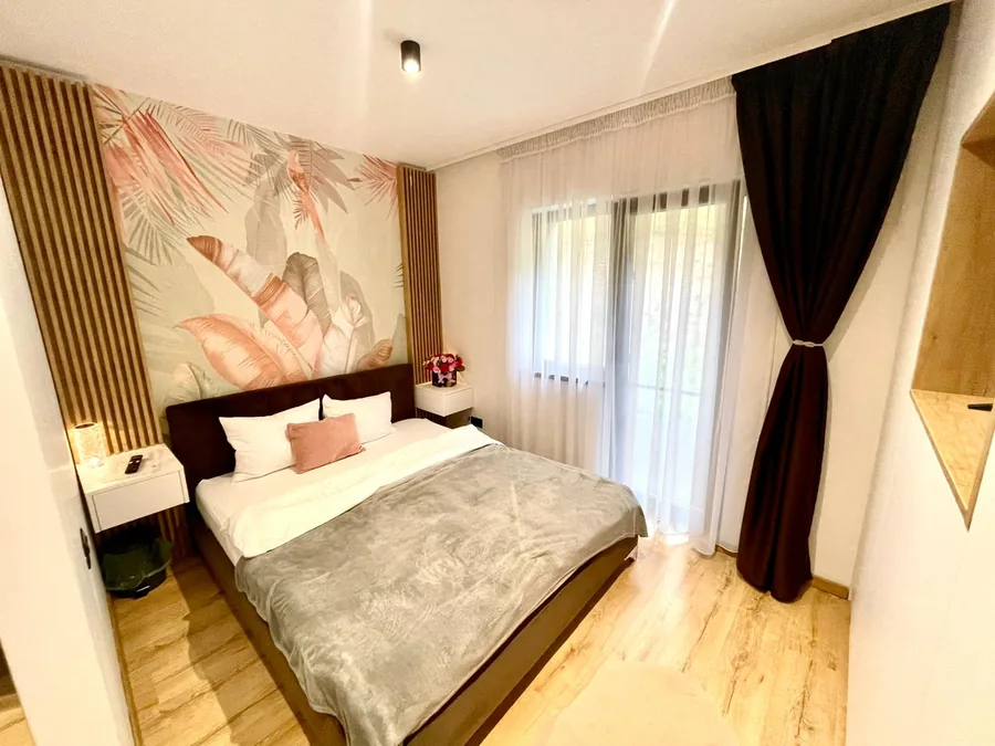 Bedroom with tropical wallpaper, double bed and lounge area